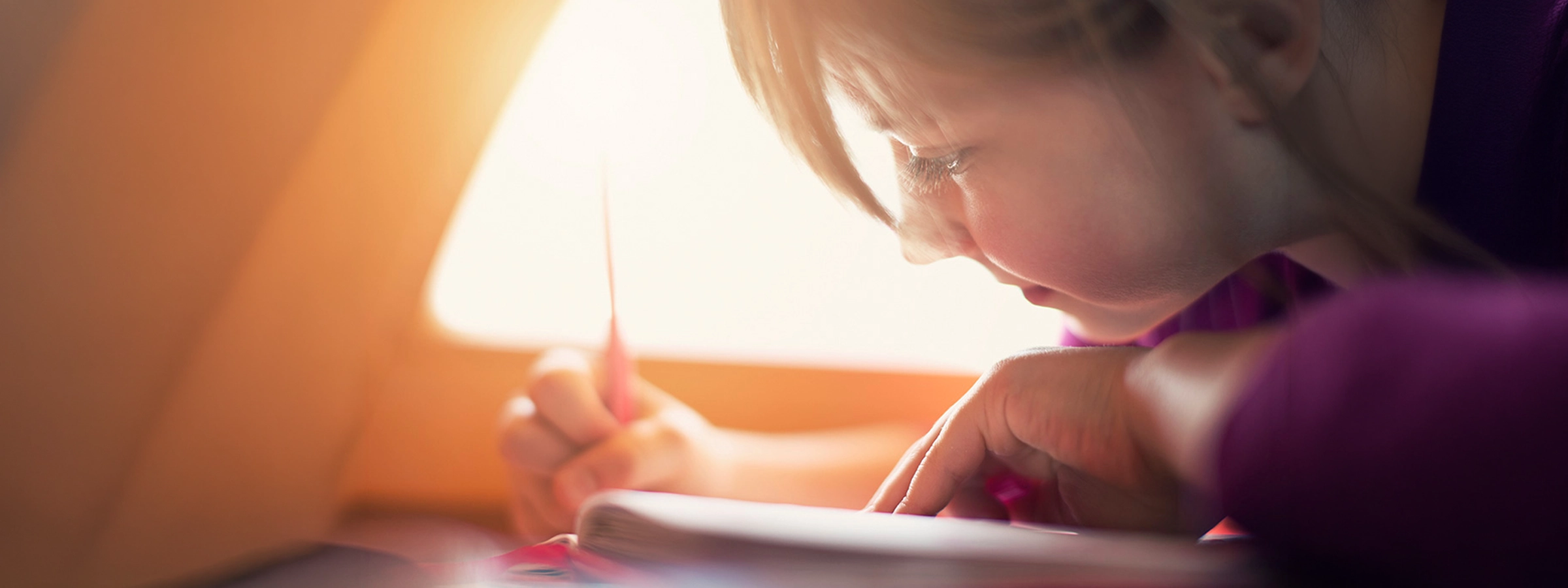 Enfant concentré en train d’écrire dans un carnet pour documenter une observation sur le développement de l’enfant.