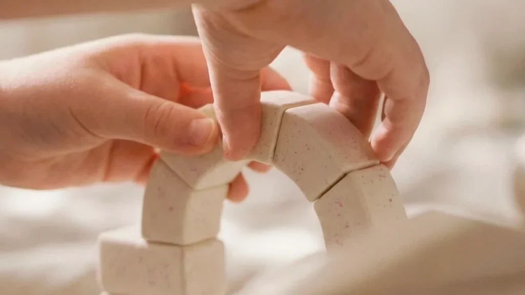 Motricité fine enfant : un enfant utilise ses deux mains pour assembler de petites pièces de construction courbes avec précision.
